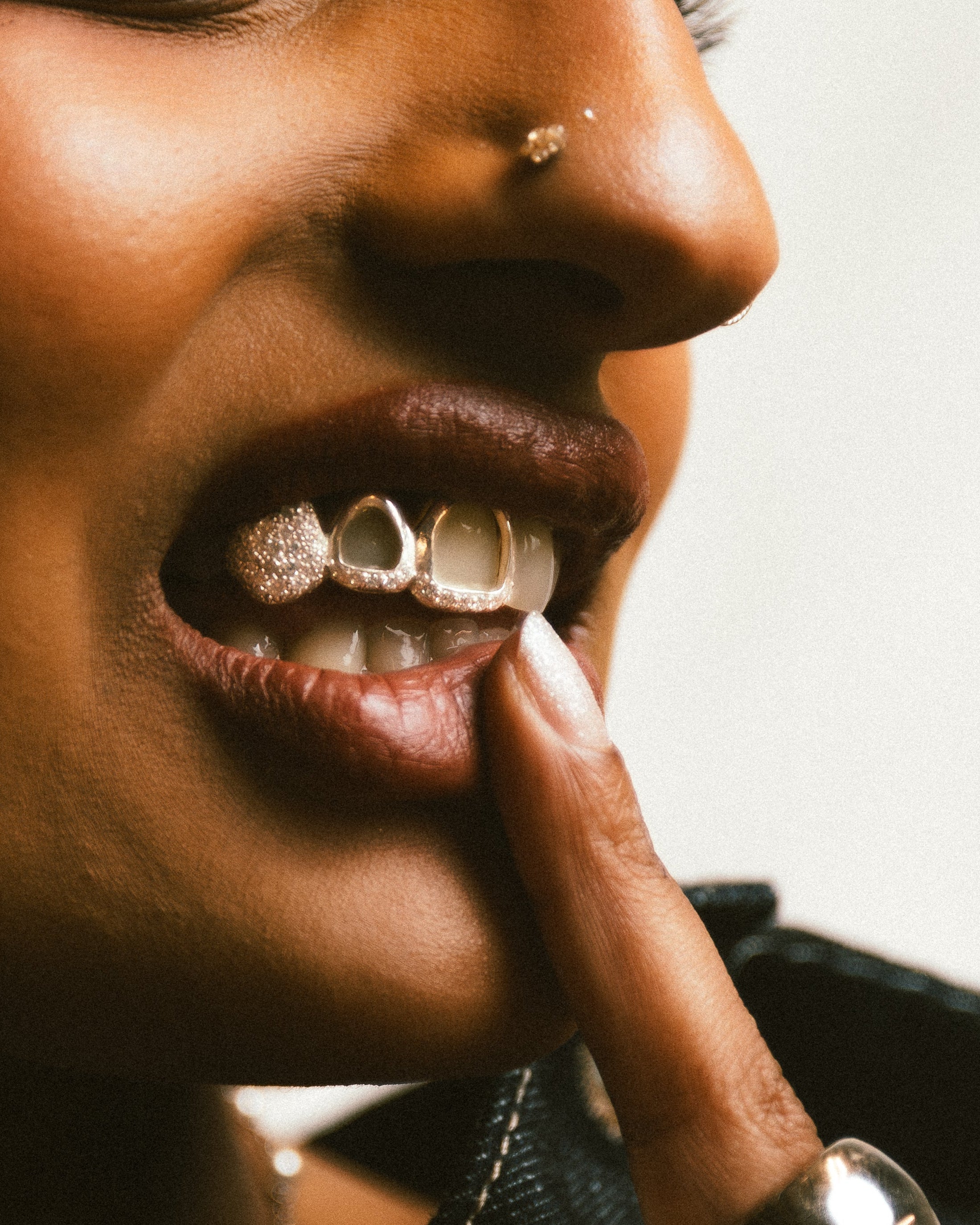 Close-up of a person wearing diamond grillz on their teeth with a blurred background