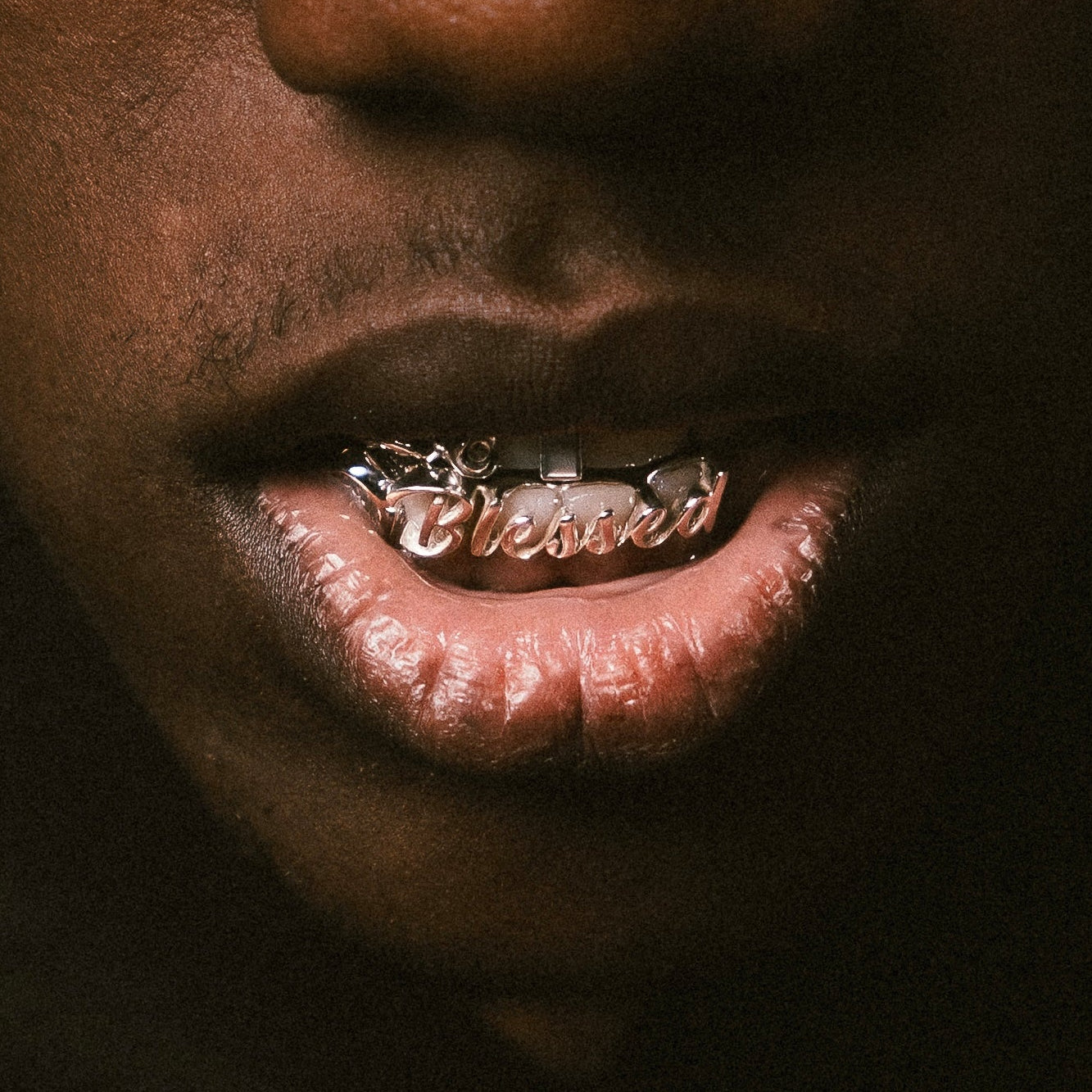 Close-up of a person's mouth with gold grillz on a dark background